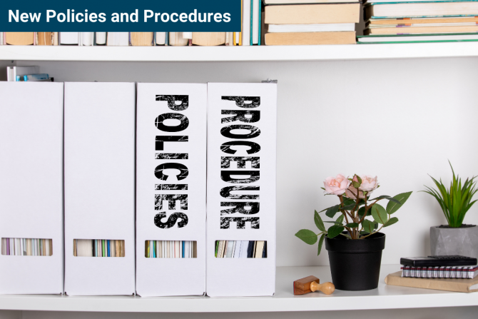 Photo of document boxes on a desk, labeled policies and procedures, next to two small plants