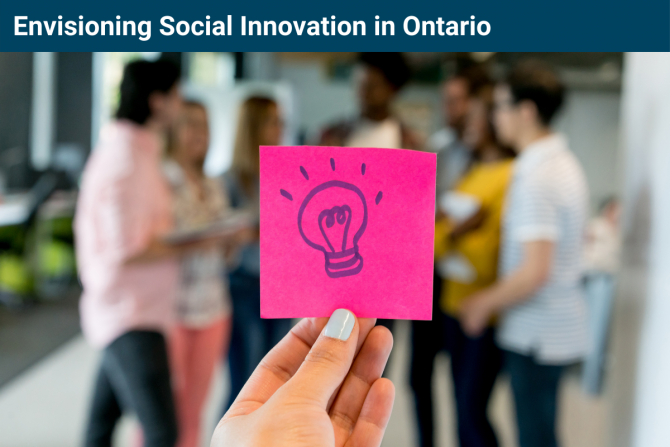 Photo of a hand holding a pink sticky note with a drawing of a lightbulb on it. In the background is a blurred group of people.